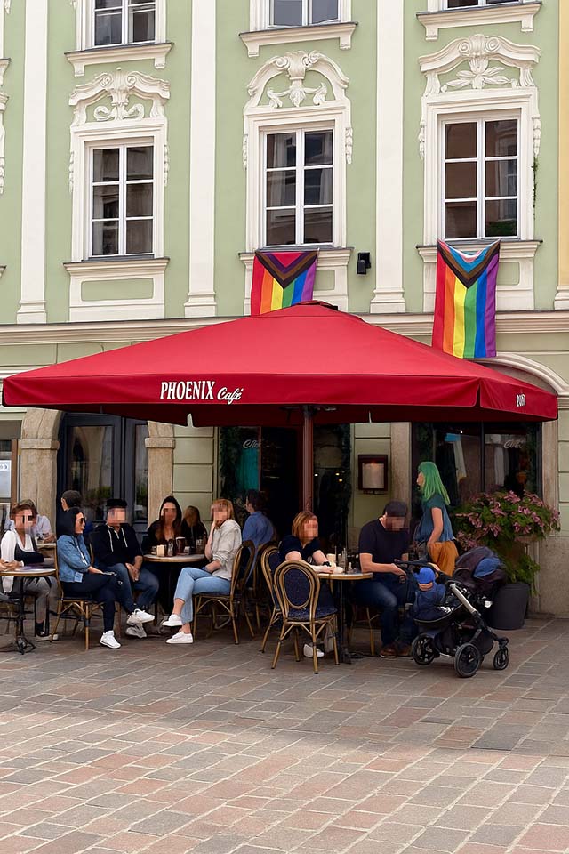 Reserviere deinen Platz im magischen Sitzgarten des Phoenix Book Café Außenbereich des Phoenix Book Café mit Gästen im Sitzgarten unter rotem Schirm